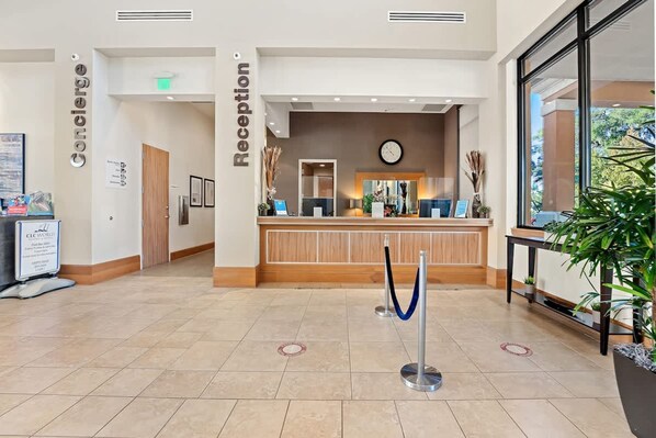 A reception area with a wooden reception desk, a clock, and a blue rope barrier. - Pet Friendly 4 BR With Hot Tub Ro2761n (Kissimmee)