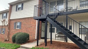 Un edificio de dos pisos con fachada de ladrillo y una escalera metálica negra que conduce a un nivel superior.