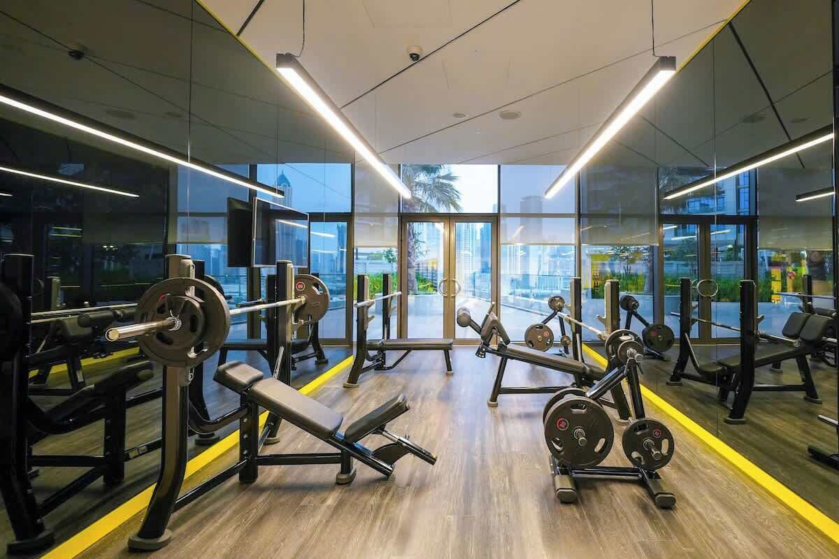 A gym with weightlifting equipment, large windows, and a view of the city.
