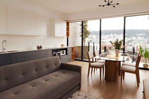 A modern kitchen with a dining area, large windows, and a city view.