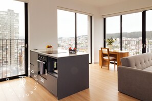 Una cocina moderna con horno empotrado y comedor con mesa y sillas de madera.