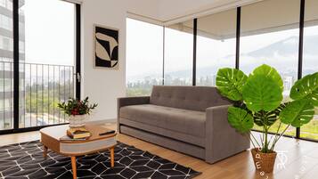 A modern living room with a grey sofa, a coffee table, and a potted plant.
