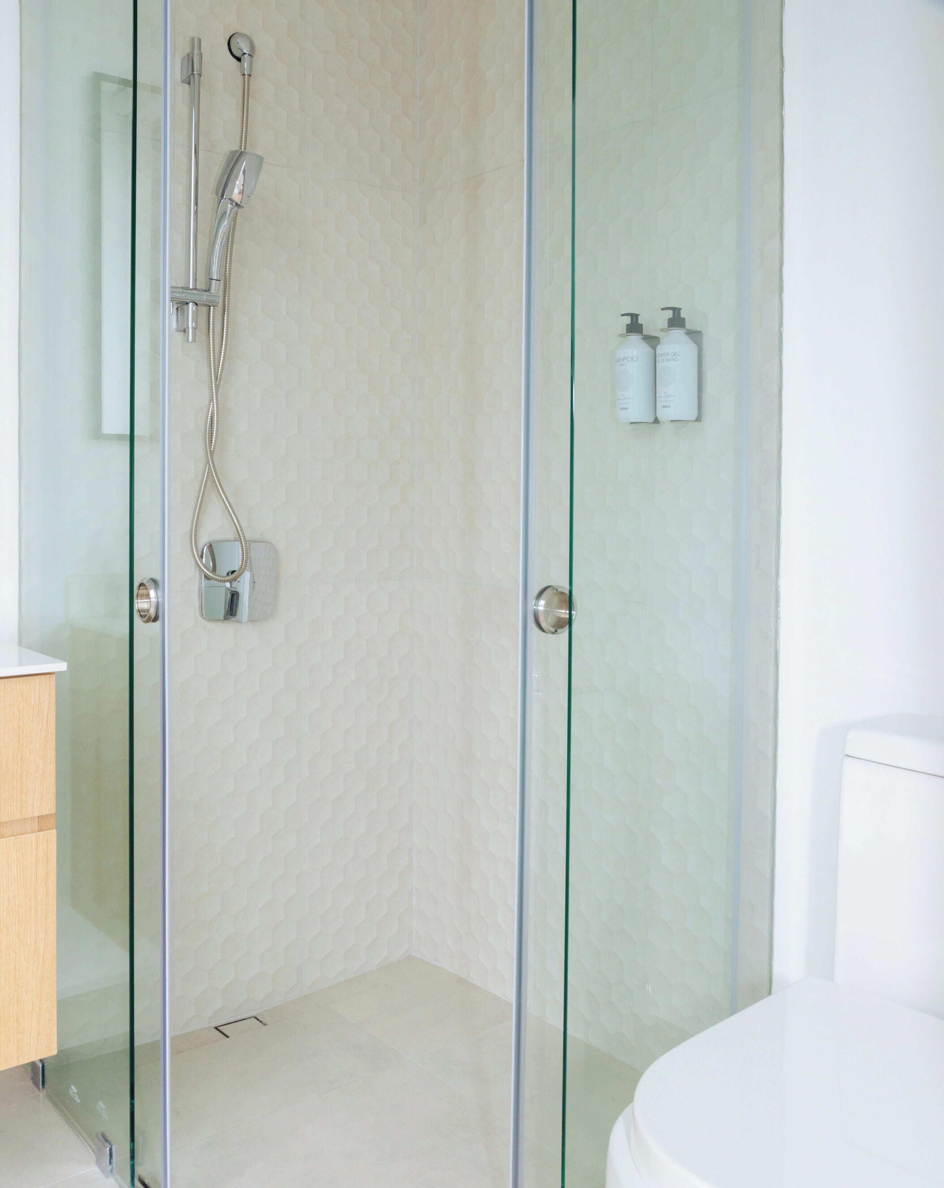 Un baño moderno con ducha envuelta en vidrio, inodoro y lavamanos.