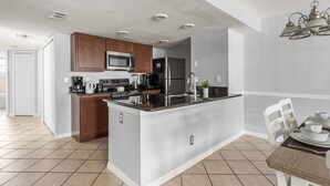 A modern kitchen with a central island, stainless steel appliances, and a dining area with a table and chairs.