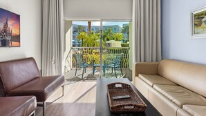 A hotel room with a balcony, a sofa, a chair, and a table with a basket. - Hotel Apt at Celebration 10 min From Disney (Celebration)