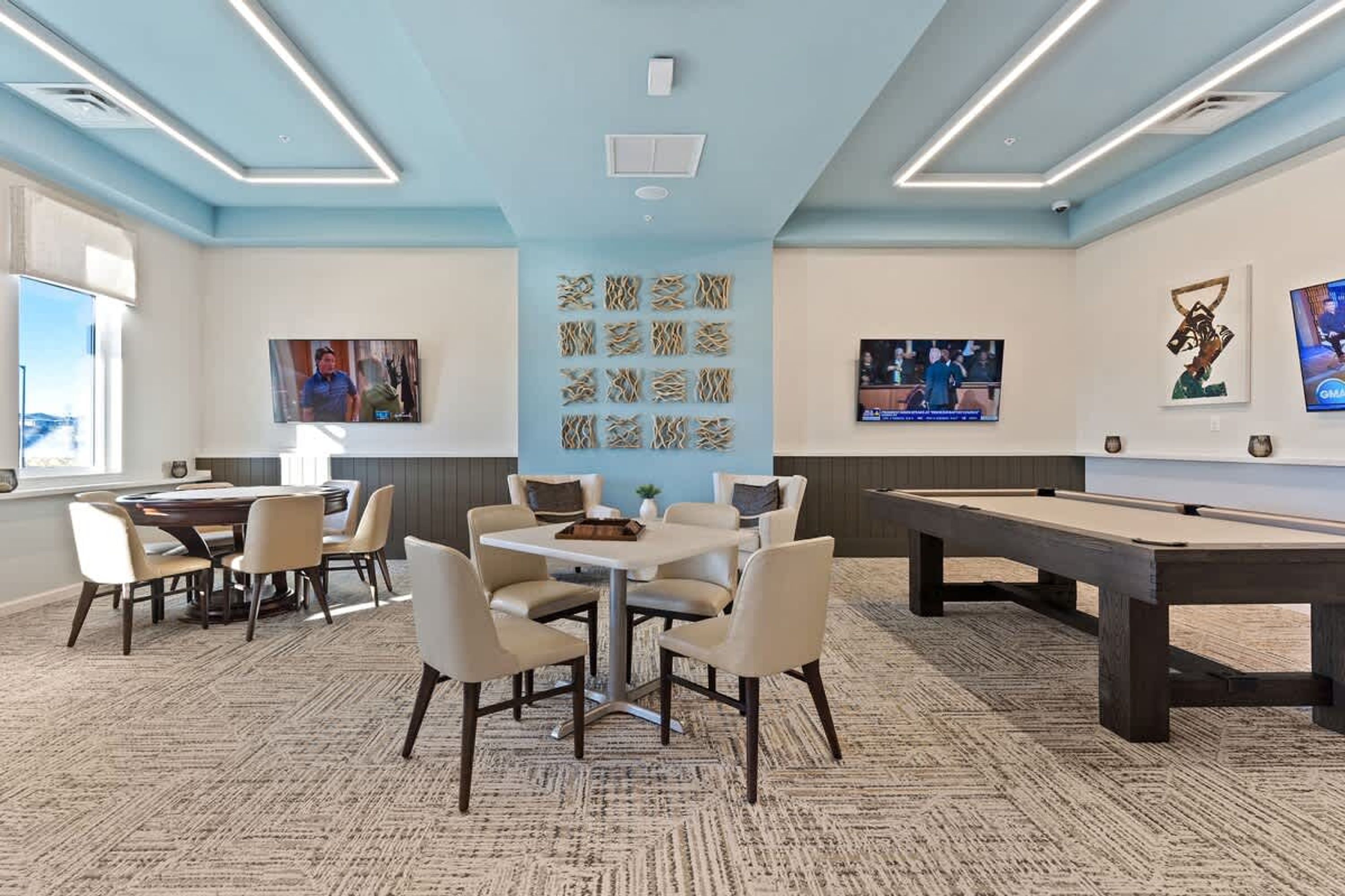 A room with a pool table, a billiards table, and a dining area with chairs and a table.