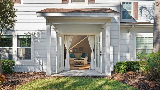 A house with a covered porch leading to a living room with a beige sofa and a coffee table. - Charming Townhouse 4 BR up to 12 People Wl8972 (Kissimmee)