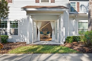 A house with a covered porch leading to a living room with a beige couch and a coffee table. - Charming Townhouse 4 BR up to 12 People Wl8972 (Kissimmee)