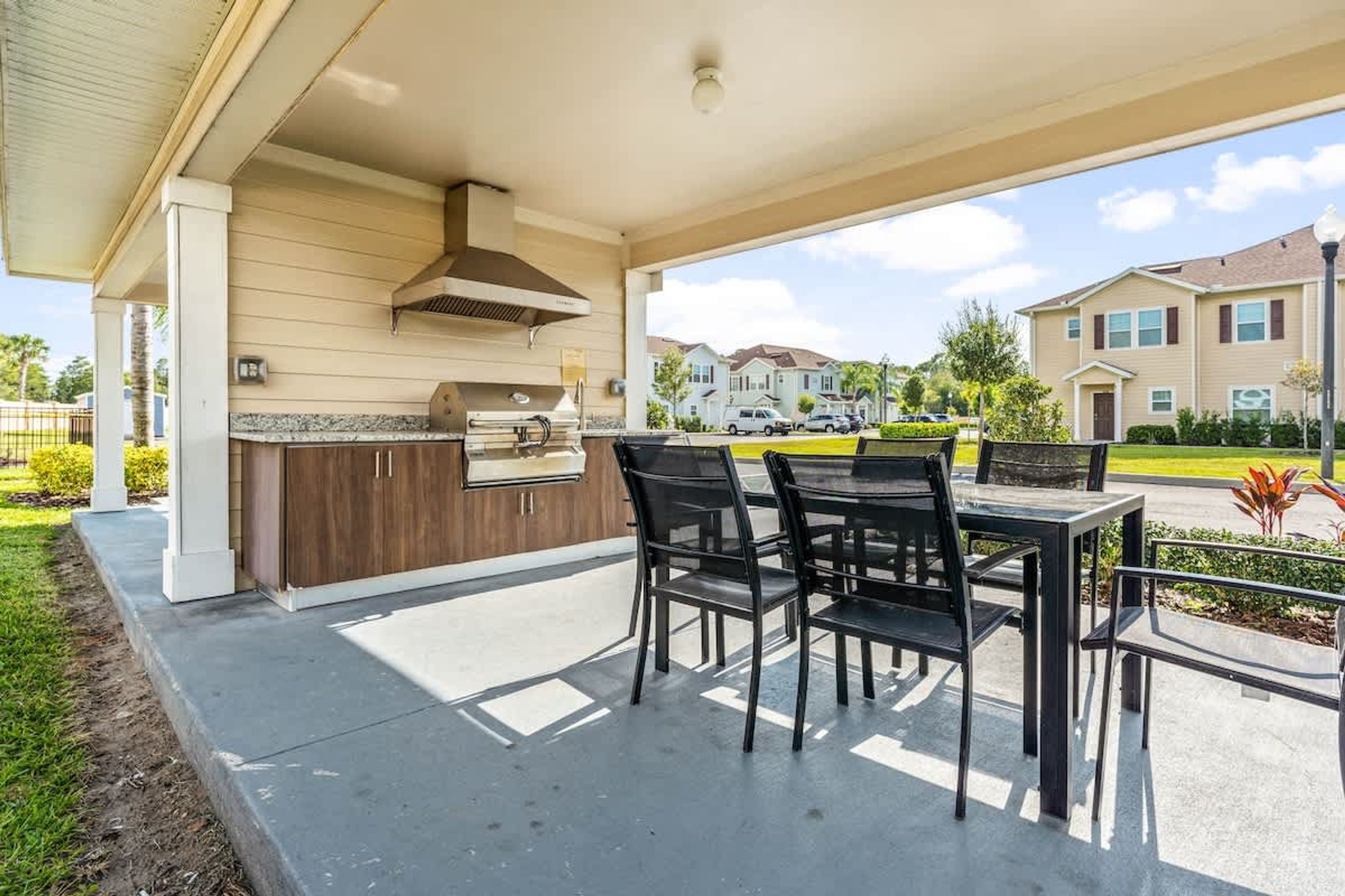 An outdoor patio with a grill, dining table, and chairs.