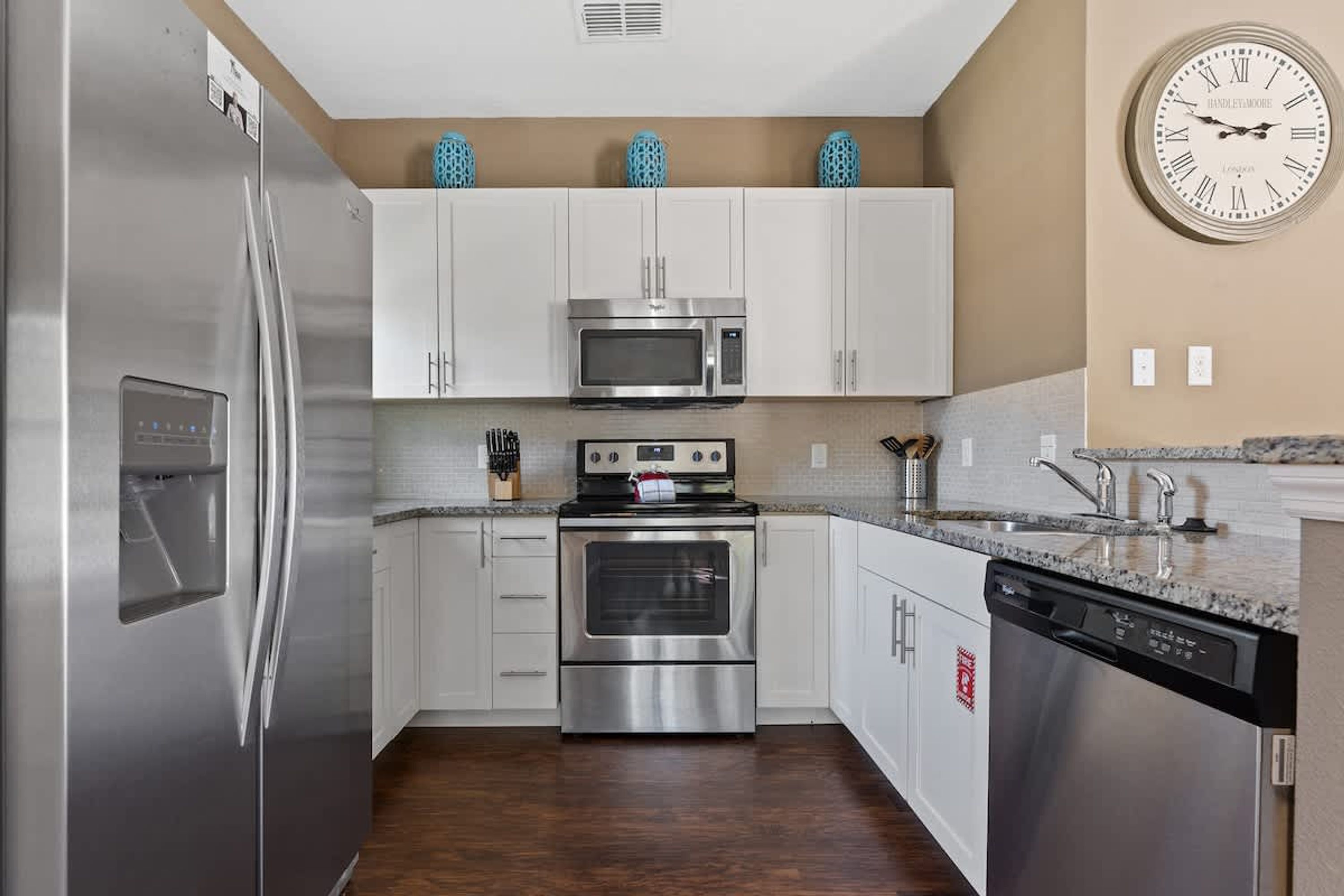 A modern kitchen with stainless steel appliances, white cabinets, and a microwave on the countertop.