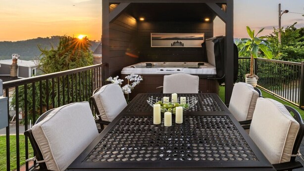 Ein Balkon mit Esstisch, Whirlpool und einer Sitzecke mit Stühlen und einer gepolsterten Bank.