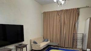 Ein Schlafzimmer mit Bett, Fernseher, Sofa, einem kleinen Tisch und Deckenventilator.