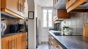 Une cuisine moderne avec des meubles en bois, un réfrigérateur en acier inoxydable, un four encastré et un plan de travail en granit.
