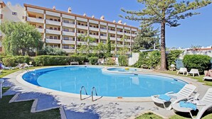 A swimming pool with lounge chairs and a building in the background. - MAR SOL Villa in Vilamoura (Loulé)