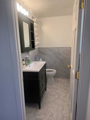 A bathroom with a white sink, dark vanity, and a toilet.