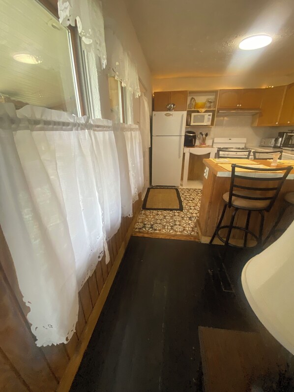 Una cocina funcional con refrigerador, microondas, estufa y taburetes de bar.