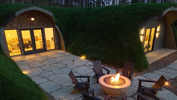 Une terrasse en pierre avec un foyer et des fauteuils Adirondack.