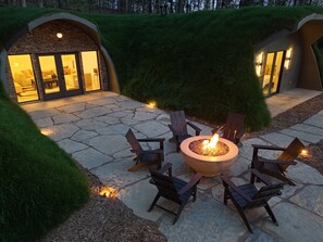 Une terrasse en pierre avec un foyer et des fauteuils Adirondack.