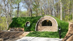 Une maison avec un toit végétalisé, des murs en pierre et une fenêtre circulaire.