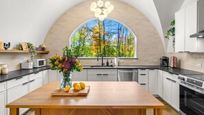 Une cuisine moderne dotée d’une grande fenêtre, de meubles blancs et d’une table à manger en bois.