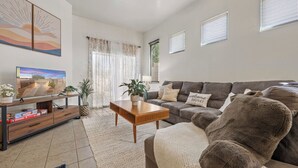A living room with a sofa, a coffee table, a TV on a stand, and a large teddy bear. - Cozy/Relaxing Home in Sierra Vista (Sierra Vista)