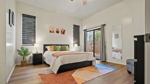 A bedroom with a bed, bedside tables, a plant, and a view through a glass door. - Cozy/Relaxing Home in Sierra Vista (Sierra Vista)