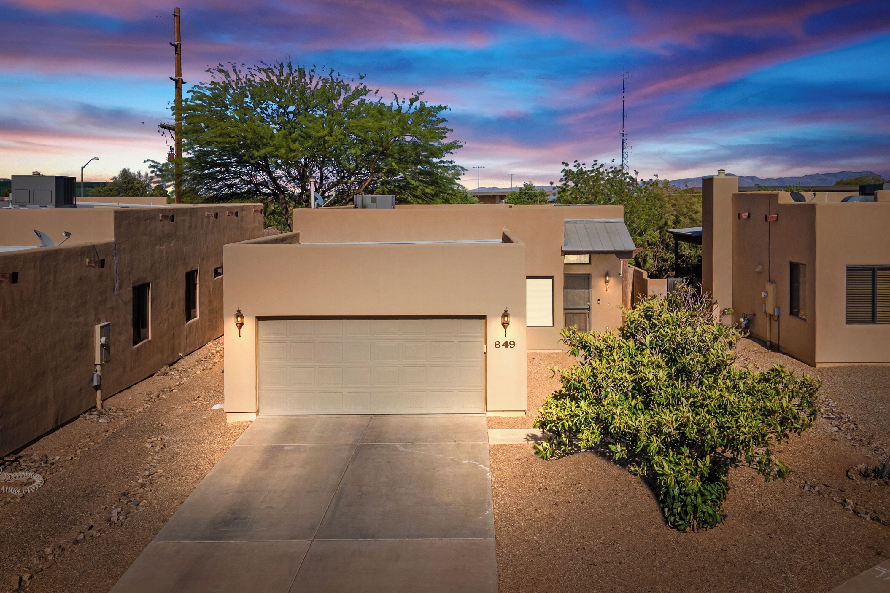 Un immeuble résidentiel moderne doté d’un garage, d’une allée bien entretenue et d’un petit jardin.