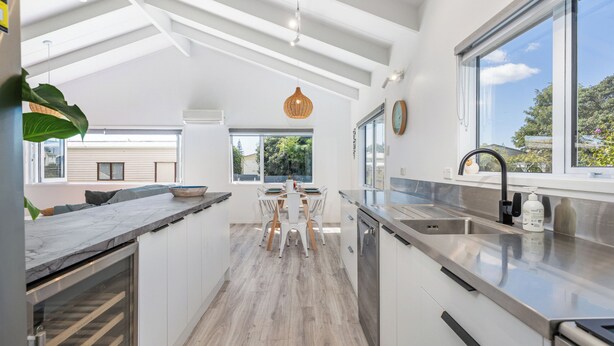 A modern kitchen with a central island, built-in appliances, and large windows offering views of the outdoors.