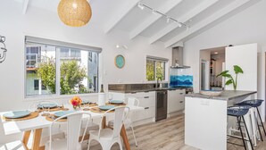 A modern kitchen with white cabinetry, a central island, and a dining area with white chairs and a table set for four.