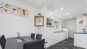 A modern kitchen with white cabinets, a dining area with a table and chairs, and a tiled floor.