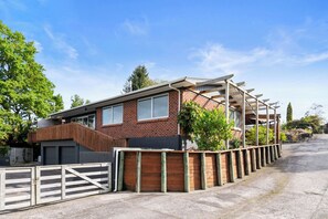 A modern brick house with a covered porch, a gated driveway, and a clear blue sky.