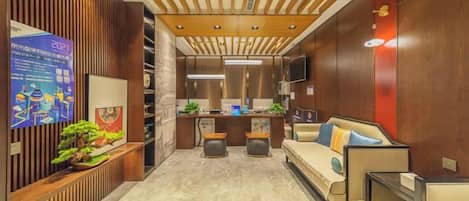 A hotel lobby with a reception desk, seating area, and a wooden accent wall.