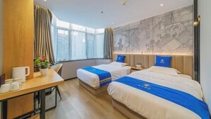 A hotel room with two beds, a desk, a chair, a window with curtains, and a wall with a map.