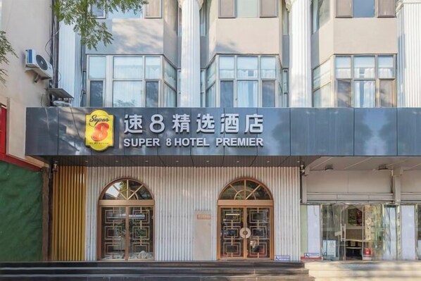 Un hotel con un letrero llamativo, grandes puertas de entrada en arco y un área de recepción techada.