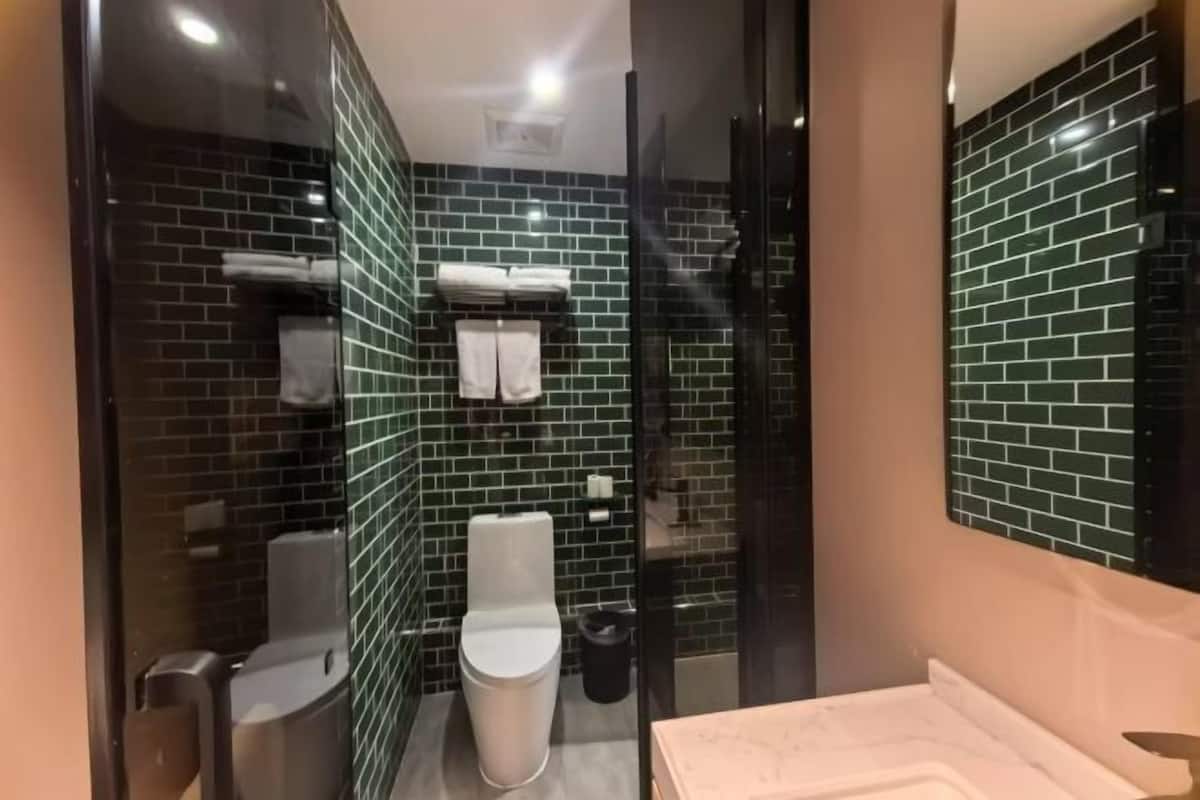 A modern bathroom with a glass partition, a white toilet, a sink, and a mirror.