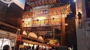 A traditional Chinese architectural structure with intricate designs and a large clock mounted on the side.