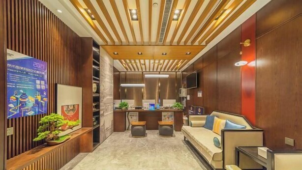 A modern hotel lobby with a reception desk, seating area, and a small kitchenette.