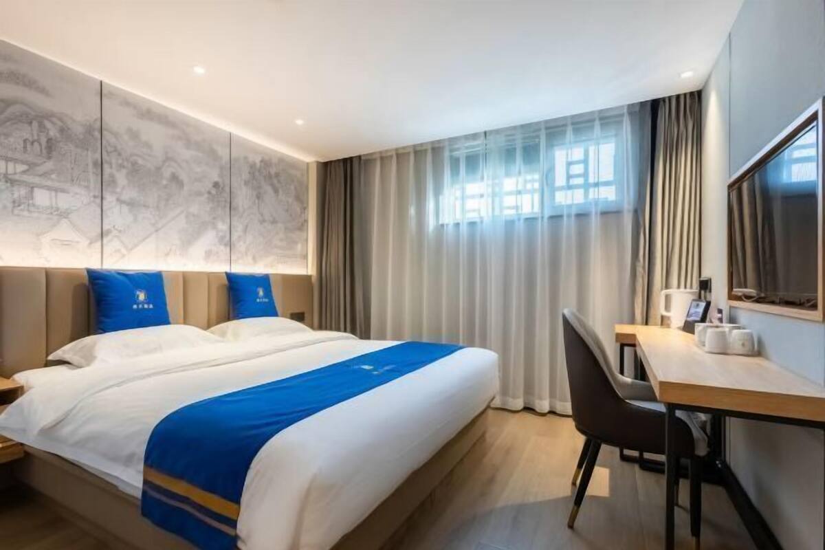 A hotel room with a large bed, a desk, and a chair.