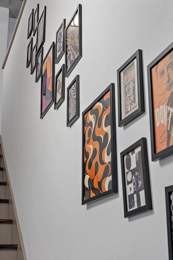 Una pared con varios cuadros enmarcados, incluyendo diseños abstractos y un cartel con texto.