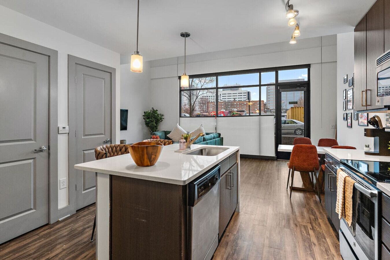 A modern kitchen with a central island, built-in appliances, and a large window offering a city view.