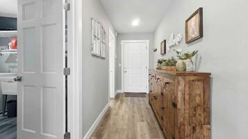 A hallway with a wooden floor, white walls, and a wooden cabinet with drawers.