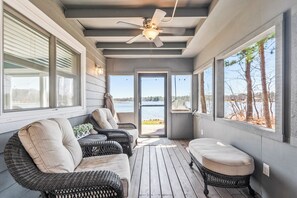 Relax on the porch with a view of the lake, surrounded by wicker furniture and a bench.
