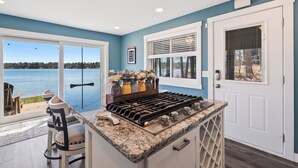 Una cocina con vista al lago, una estufa a gas y un comedor con sillas.