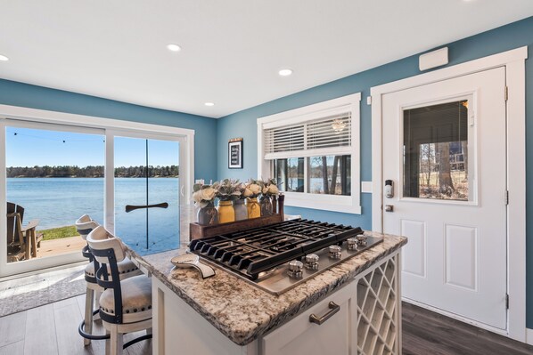 Enjoy a serene view of the water from this kitchen, featuring a gas stove, ample counter space, and a wine cooler.