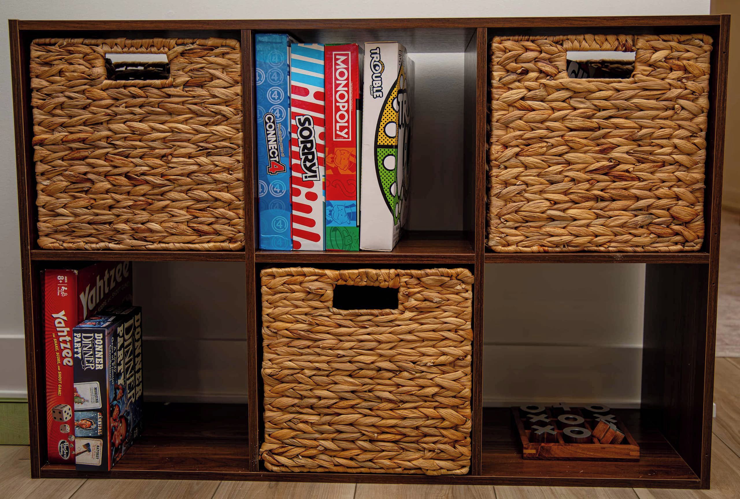 Un estante de madera con cestas tejidas y juegos de mesa.