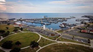Vista aérea de un puerto deportivo con muelles, barcos y un faro.