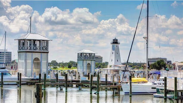 Un puerto deportivo con barcos amarrados, un faro y una estructura de torre.