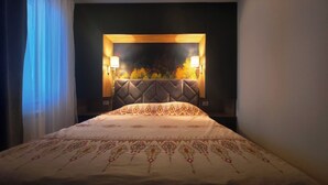 Een hotelkamer met een bed, een hoofdeinde met een lamp en een raam met gordijnen.
