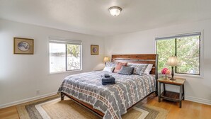A bedroom with a bed, two bedside tables, a window, and a door. - Walk to Beaches: Waterfront Home in Port Orchard! (Port Orchard)