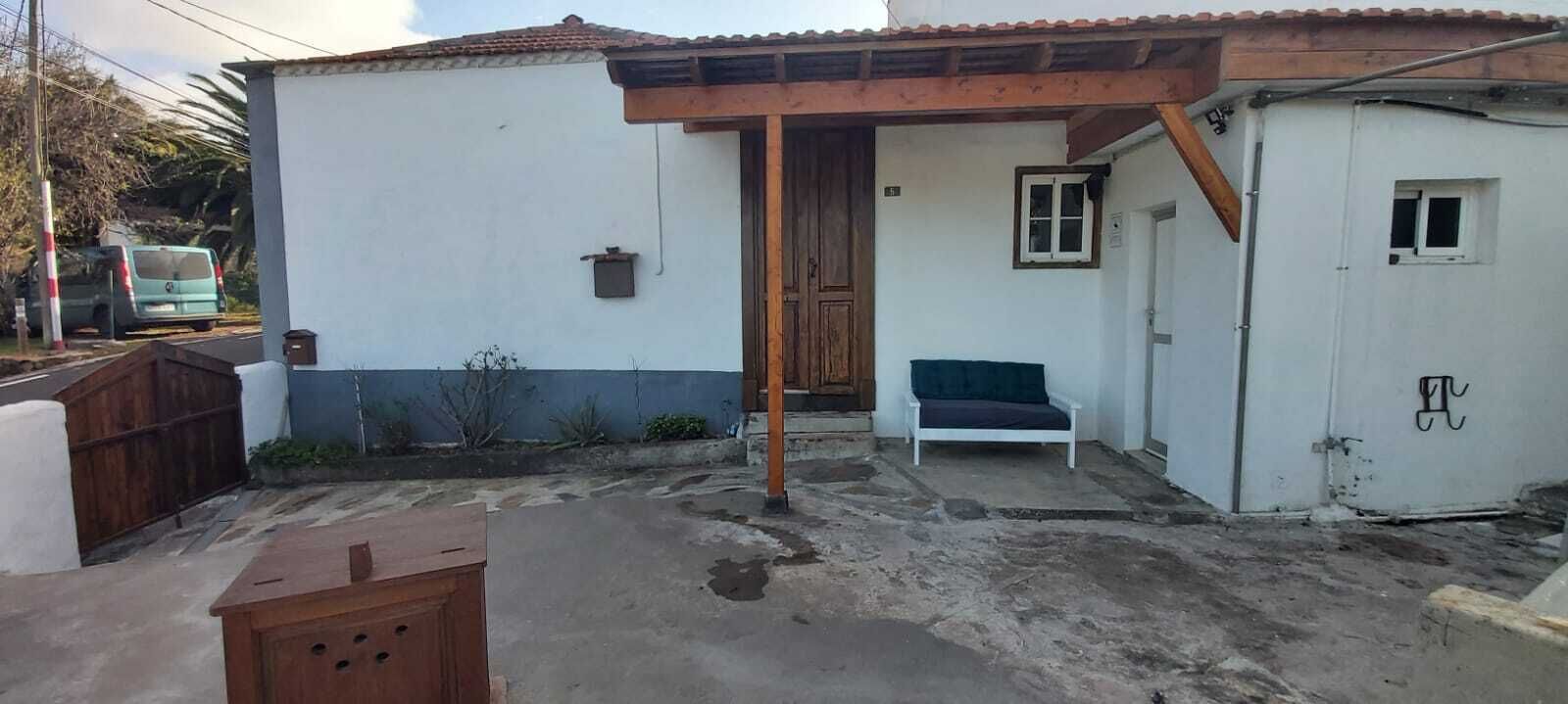 Une petite maison dotée d’un patio, d’un banc en bois et d’un petit bâtiment blanc attenant à la structure principale.